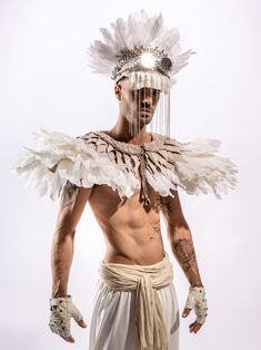 a man with white feathers on his head and chest, standing in front of a white background