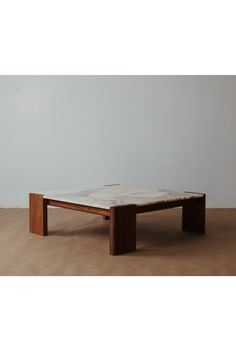 a coffee table sitting on top of a hard wood floor next to a white wall