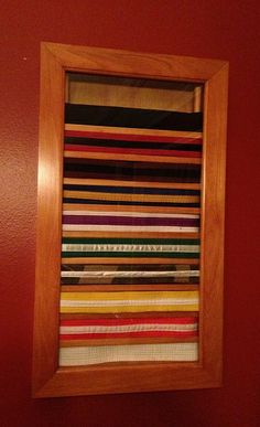 a wooden frame hanging on the side of a red wall next to a window covered in strips of fabric