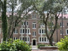 an old brick building with many windows and trees