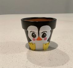 a small black and white cup with a penguin face painted on it's side