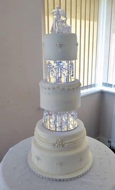 a three tiered white wedding cake on top of a table in front of a window