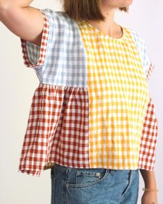 a woman with her hair in a ponytail wearing a yellow and white checkered top