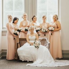 a bride and her bridals posing for a photo in front of a window