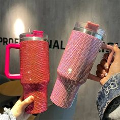 a person holding a pink and red coffee mug next to another cup with the same design on it