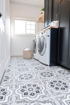 a washer and dryer sitting in a laundry room next to black cupboards