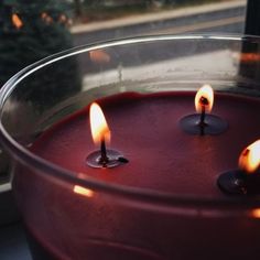 three lit candles in a glass bowl on a window sill