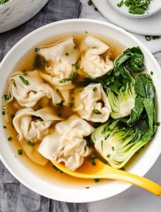 dumplings with broccoli are in a white bowl on a marble countertop