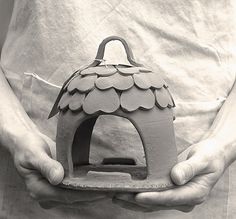 black and white photograph of a person holding a clay birdhouse