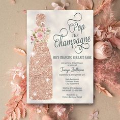 the champagne bridal party is set up on top of pink flowers and leaves, with an elegant champagne bottle