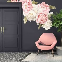 a pink chair sitting in front of a door with white flowers on the wall behind it