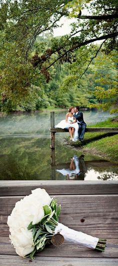 a bride and groom sitting on a bench next to the water with their wedding bouquet