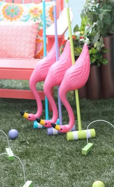 two pink flamingos standing next to each other in the grass