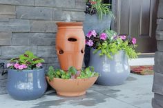 three planters with flowers in them are sitting on the front porch next to each other