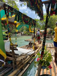 people standing on bamboo rafts in the water at an amusement park with colorful decorations