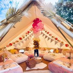 the inside of a tent decorated with pink and white decorations, balloons and streamers