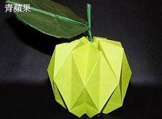 an origami apple with green leaves on it