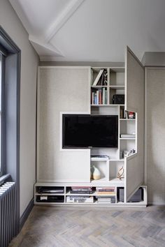 an entertainment center with bookshelves, television and other items on it in a living room