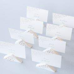 white place cards with gold dots on them are placed next to each other in rows