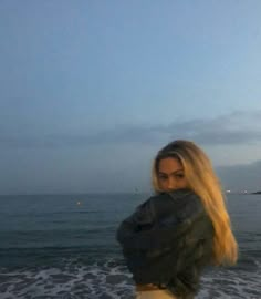 a woman standing on top of a beach next to the ocean