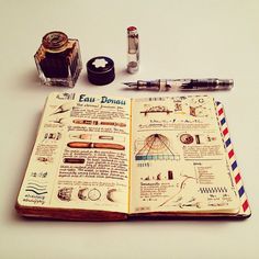 an open notebook sitting on top of a table next to some pens and other items