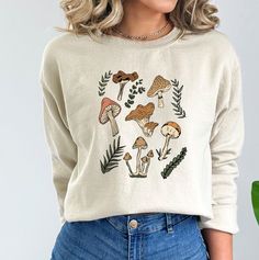 These mushroom sweatshirts are perfect all year round! They are great for layering. These sweatshirts are 50% pre-shrunk cotton, 50% polyester.  Wash on cold, dry inside out. Do not iron over design.  Processing time is 7-10 business days plus an additional 2-5 business days for standard shipping. Please message me if you need it sooner and I can see if I have the inventory on hand already. Cotton Fall Sweatshirt With Mushroom Print, Cotton Sweatshirt With Mushroom Print For Fall, Casual Fall Sweatshirt With Mushroom Print, Casual Mushroom Print Sweatshirt For Fall, Cute Fall T-shirt, Cotton Crew Neck Sweatshirt With Mushroom Print, Casual Crew Neck Sweatshirt With Mushroom Print, Relaxed Fit Fall Tops With Mushroom Print, Casual Long Sleeve Top With Mushroom Design