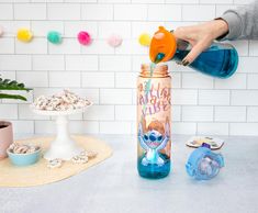 a person is pouring sugar into a bottle with an orange lid and sprinkles on it