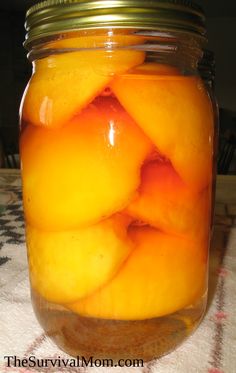 a jar filled with sliced peaches on top of a table