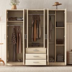 an open wardrobe with clothes hanging on the doors and drawers, in front of a white wall