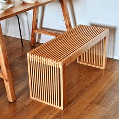 a wooden bench sitting on top of a hard wood floor next to a table and chair