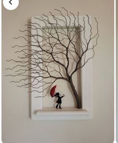 there is a small figurine holding an umbrella in front of a tree on the wall