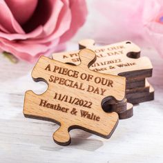 personalized wooden puzzle pieces with names and date engraved on each piece, sitting next to a pink rose