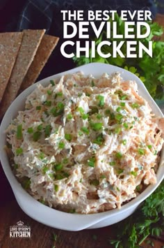 a white bowl filled with chicken salad and garnished with parsley on the side