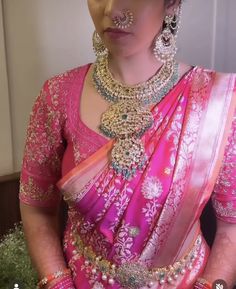 a woman wearing a pink sari and jewelry