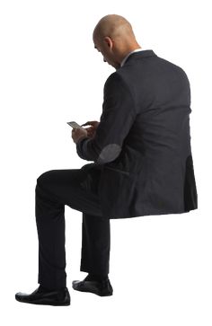 a man in a suit sitting on a chair looking at his cell phone