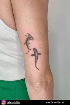 a woman with a tattoo on her arm and two dolphins in the water behind her