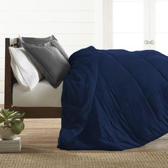 a blue comforter on a bed next to a potted plant