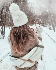 a woman is sitting in the snow holding a candy cane