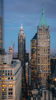 the city skyline is lit up at night, with skyscrapers in the foreground