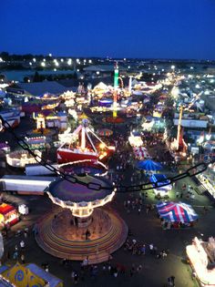 an aerial view of a fairground at night with many rides and carnival booths in the background