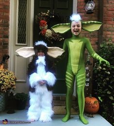 two children in costumes standing on the front porch