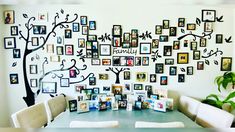 a dining room table with pictures on the wall and family tree above it, surrounded by white chairs