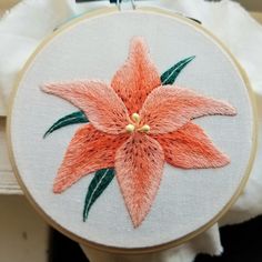 a close up of a flower on a piece of cloth in a hoop with scissors