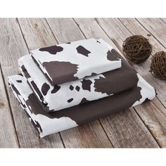 three pieces of brown and white cow print fabric on wooden floor next to ball of twine