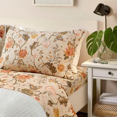 a bed with floral sheets and pillows in a bedroom