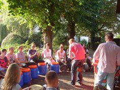 a group of people sitting around buckets on the ground