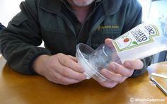 a man is holding a plastic container with something in it on the table next to him