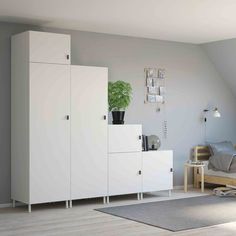 a bedroom with white furniture and a green plant in the corner on top of it