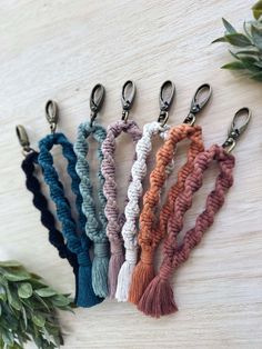 six different colors of rope with tassels hanging from each side on a wooden surface