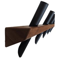 a wooden shelf with three black knives on it's sides and one is leaning against the wall